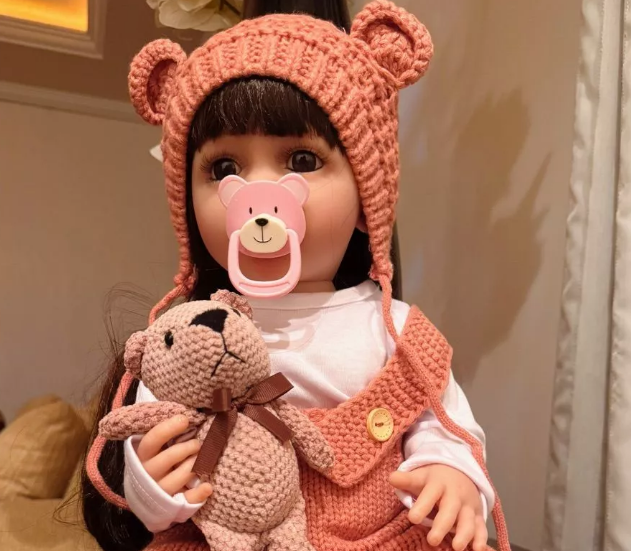 Detalhe do cabelo de um bebê reborn com touca rosa, ilustrando a diferença de qualidade e impacto no preço entre o enraizamento manual e perucas.