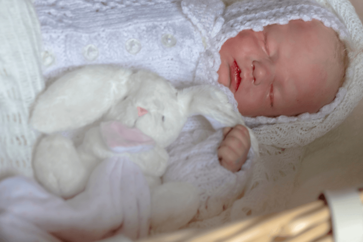 Close do rosto de uma bebê reborn original dormindo, destacando a pintura realista e os detalhes de pele que diferenciam uma arte autêntica de uma falsificação.