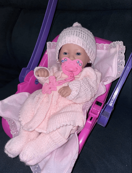 Bebê reborn finalizado por uma artista cegonha, com roupa de lã rosa e chupeta, demonstrando o estilo da criadora.